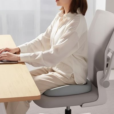 Coussin ergonomique chaise femme assise sur chaise grise