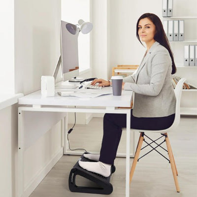 Repose pied pour bureau | AdjustStep femme assise a son bureau les pied dessu