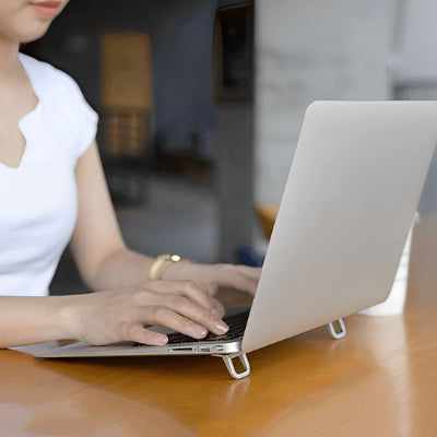 Support bureau pour ordinateur portable pliable en aluminium utilisé avec un ordinateur portable sur un bureau. Son design compact et ergonomique surélève l'écran pour favoriser une meilleure posture, réduire les douleurs au cou et au dos et améliorer la ventilation de l'appareil. Léger, discret et facile à transporter, il est idéal pour le télétravail, le bureau, les études et les déplacements.