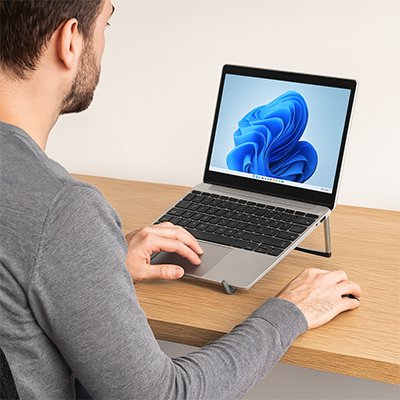 homme travaillant sur son ordinateur portable posé sur un Support ordinateur portable sur son bureau en bois