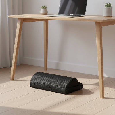 Coussin repose-pieds Nébula Mesh noir sous un bureau en bois clair