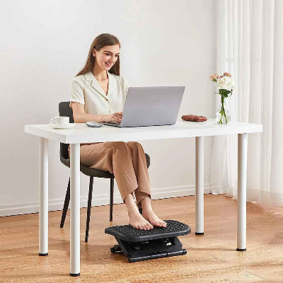 jeunne femme assise a son bureau avec les pied sur le repose pied bureau