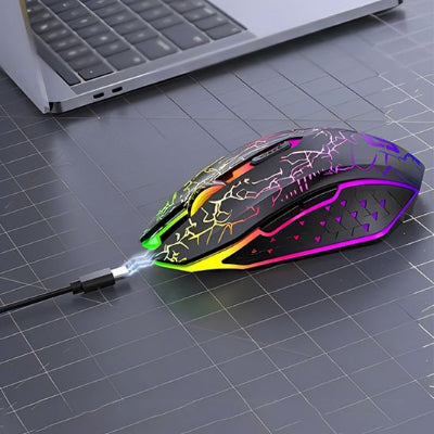 Souris gamer silencieuse noire reliée par son câble de recharge à un ordinateur